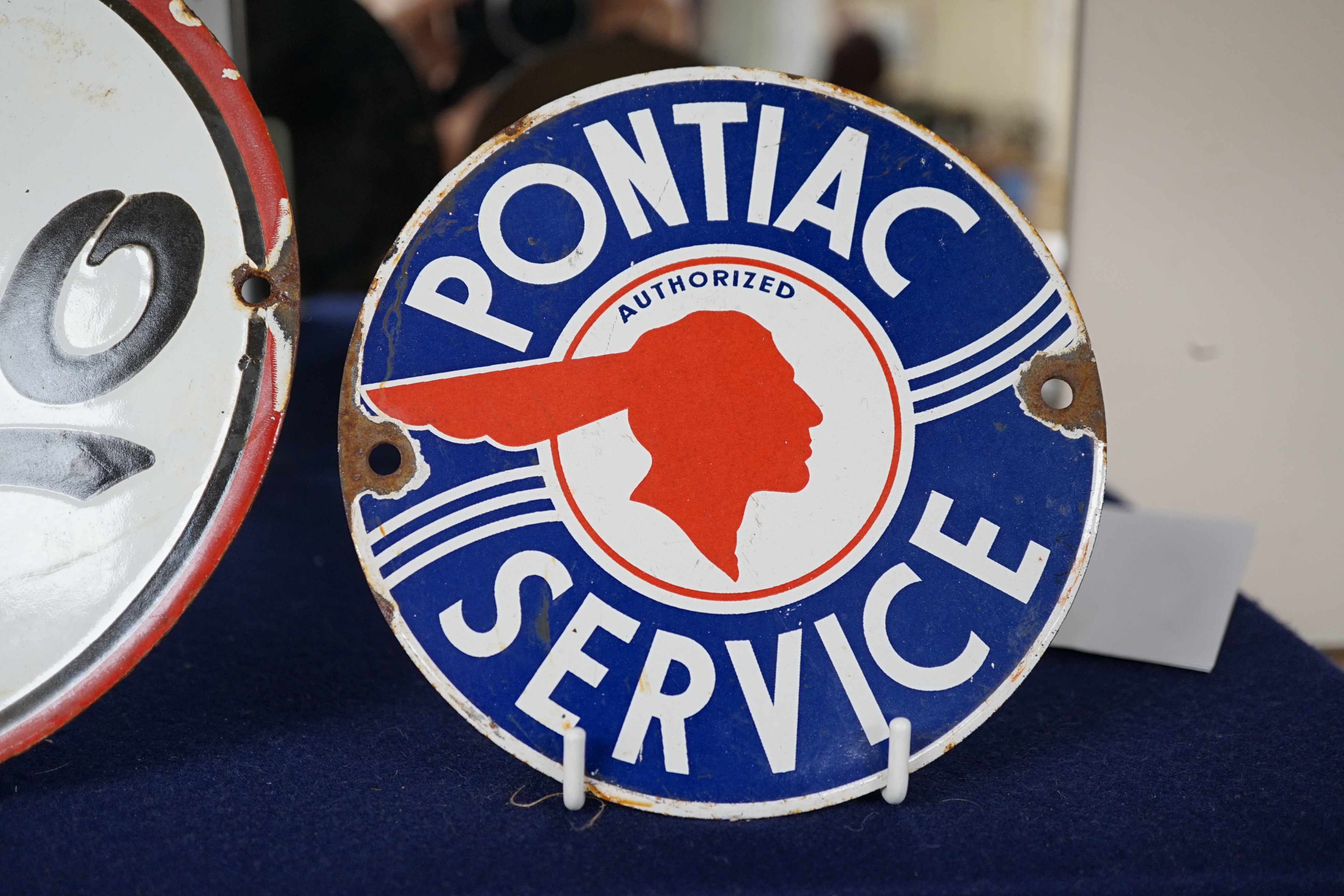 Automobilia interest; an early 20th century Esso enamel sign, diameter 20cm, and a Pontiac Service enamel sign, diameter 15cm. Condition fair to good, some chipping around the screw holes and surface rust to exposed meta